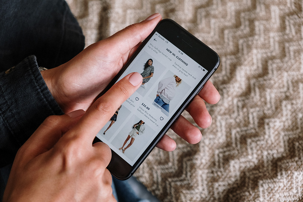 Persoon zoekt kleding op gsm voor e-commerce. Illustratie van mobiel winkelen en online kledingontdekking.